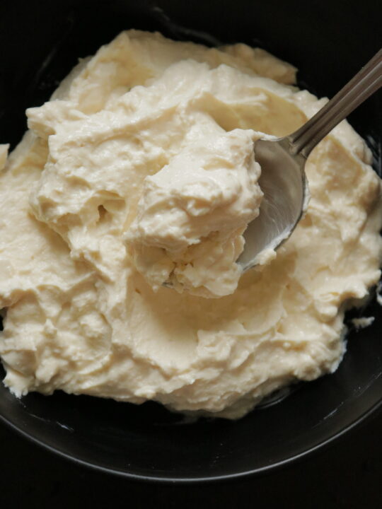 a bowl of cream cheese with a spoon of cheese