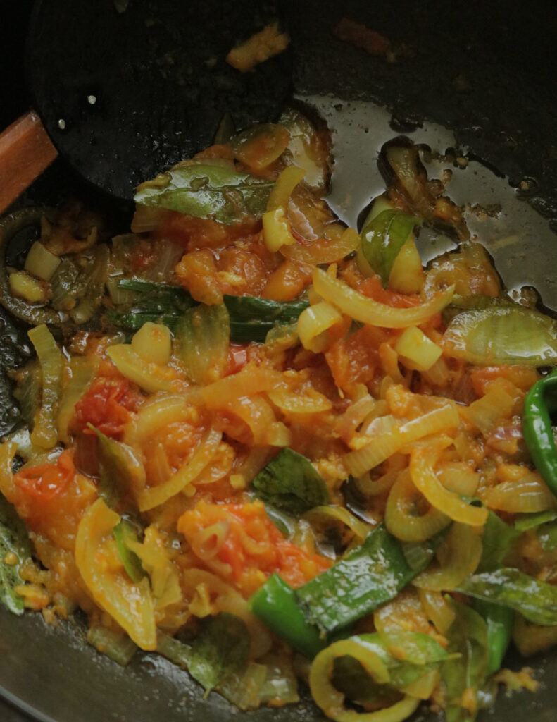 cooking the sliced onions, tomatoes, curry leaves in oil until they are soft to cook the meatball curry.