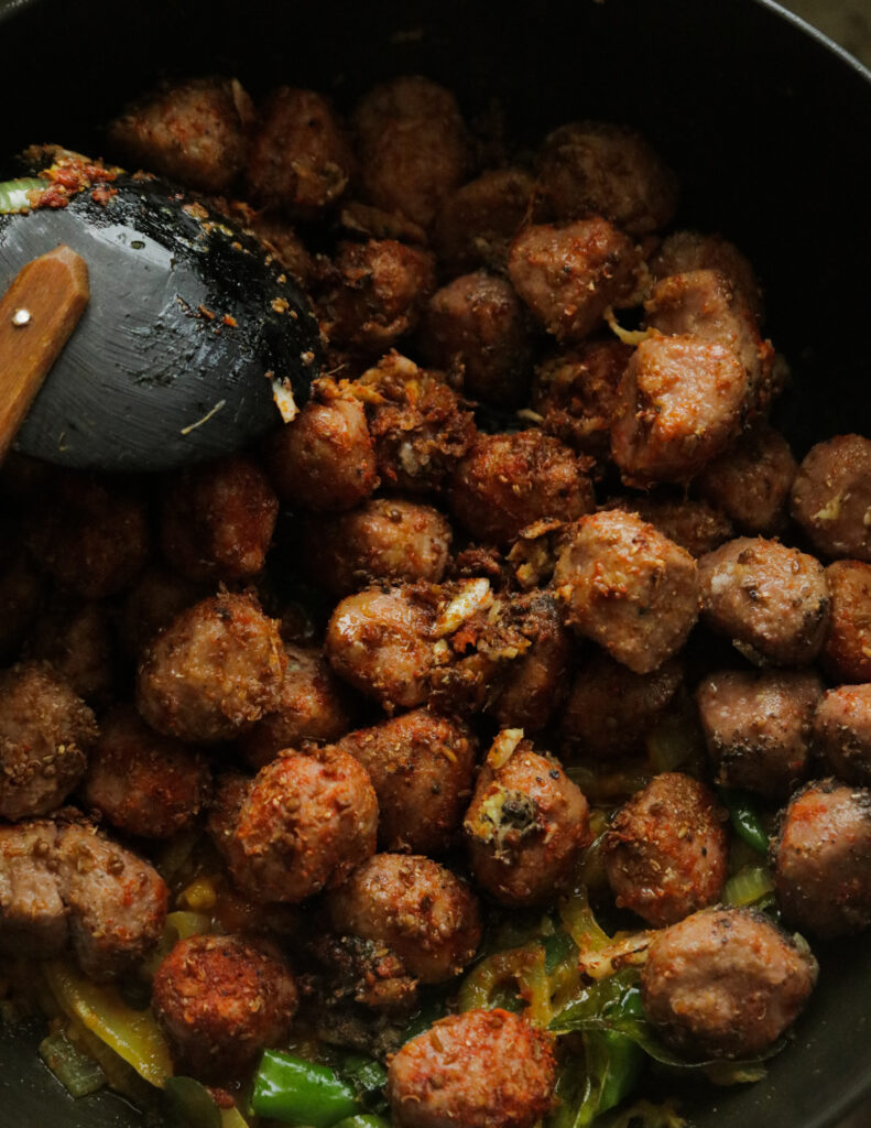 cooking the meatball curry with the spices and curry leaves and other ingredients.