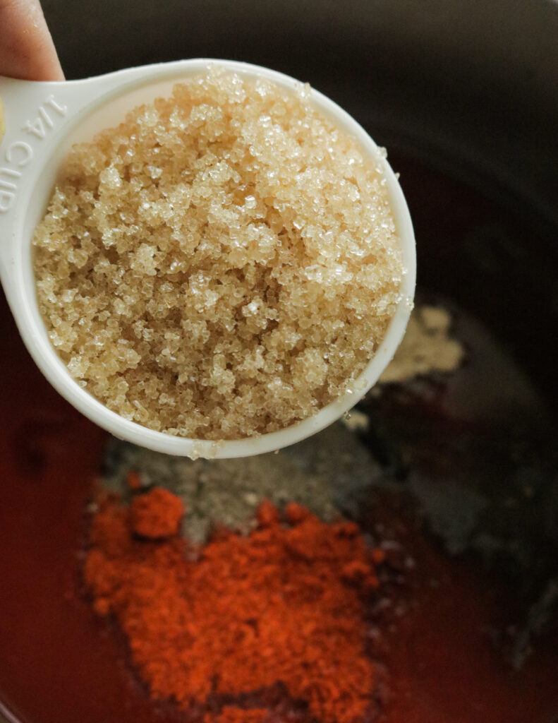 adding brown sugar to cook barbecue sauce
