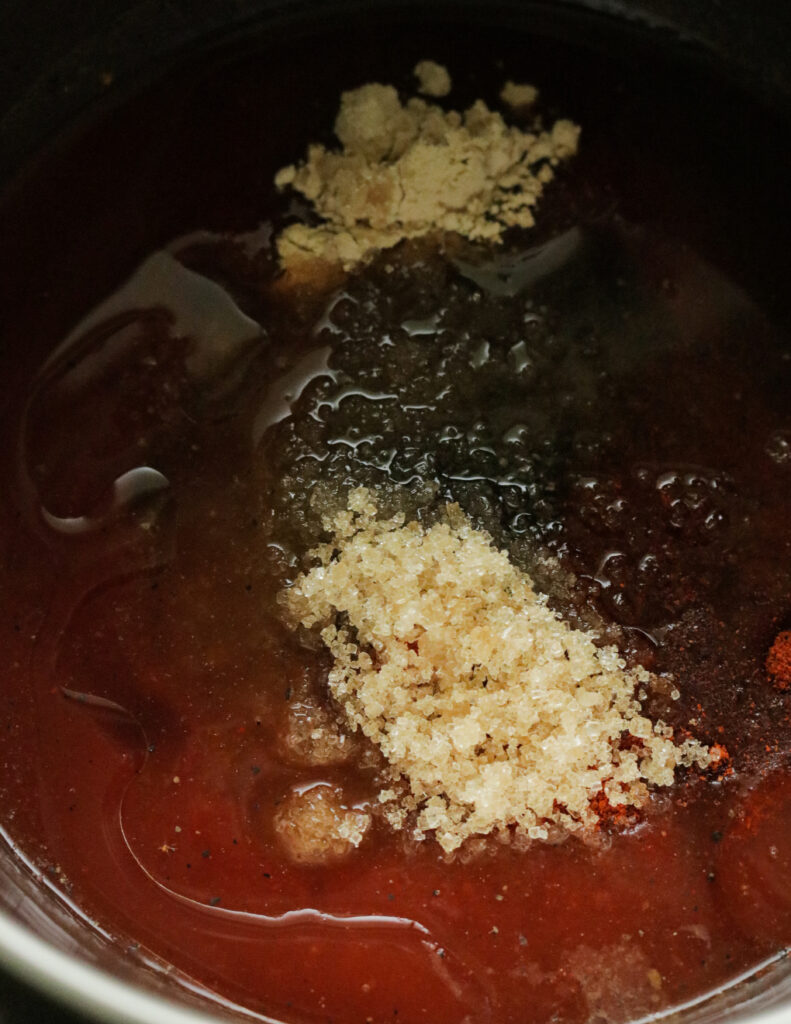 adding all ingredients to the tomato sauce to make the sweet and spicy BBQ sauce.