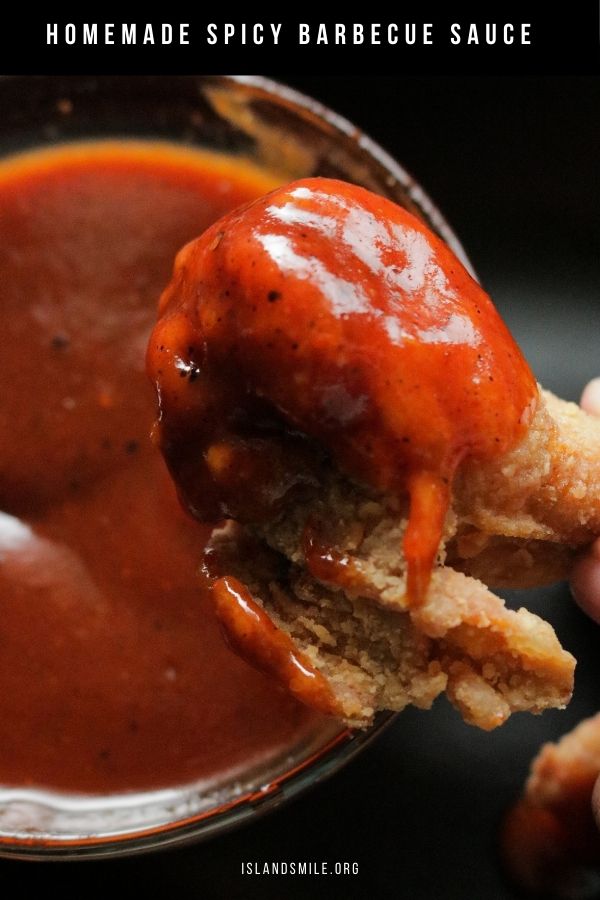 dipping crispy fried chicken wings in spicy BBQ sauce.