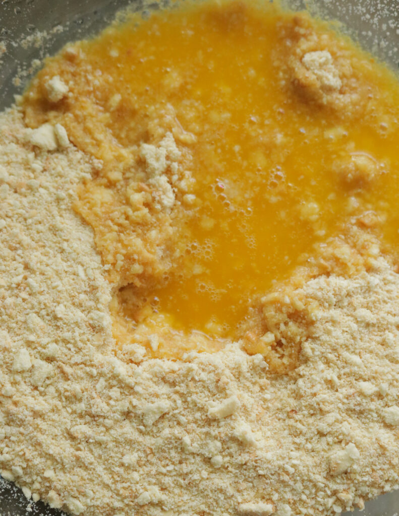 adding the butter to the crushed graham cracker to make the lemon bar crust.