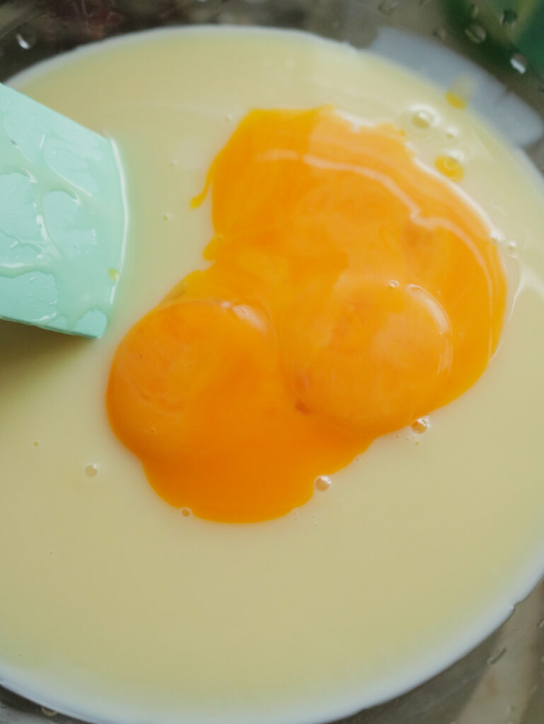 adding egg yolk to condensed milk to make the lemon bars.