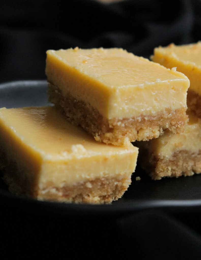 slices of lemon bars on top of each other and placed on a black plate 