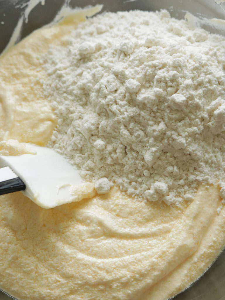 adding flour to the butter mixture to make the ribbon cake