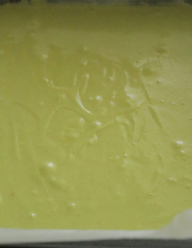 adding the green colored batter to a baking pan