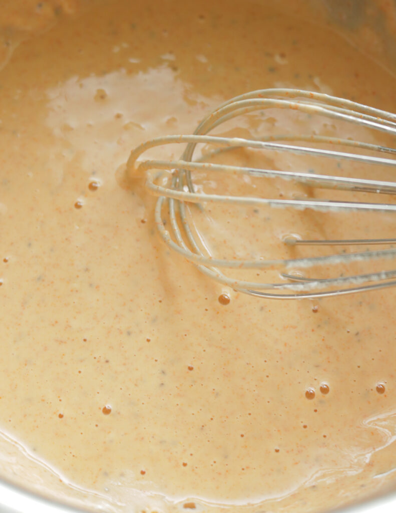 whisking a batter to make chilli chicken.