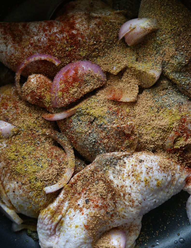 covering the chicken quarters with soices, onions to make the broth for chicken mandi rice.