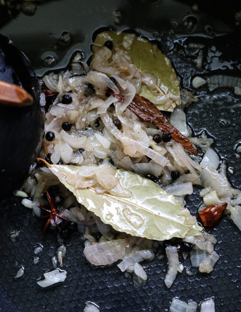 tempering onions, bay leaves, peppers, star anise to cook chicken mandi rice.