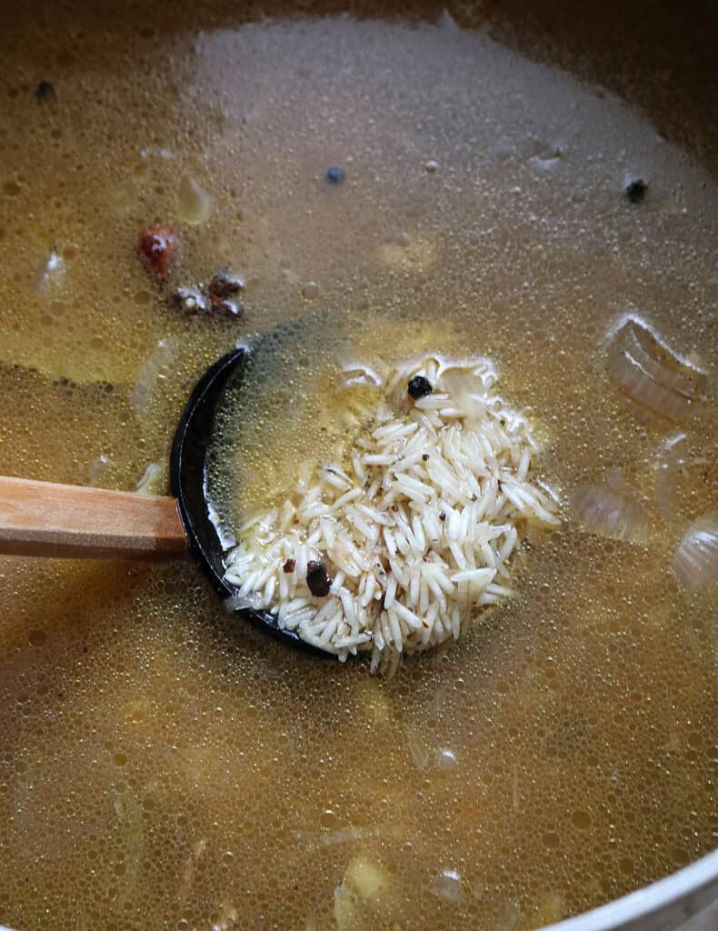 adding the chicken broth to cook the chicken mandi rice.