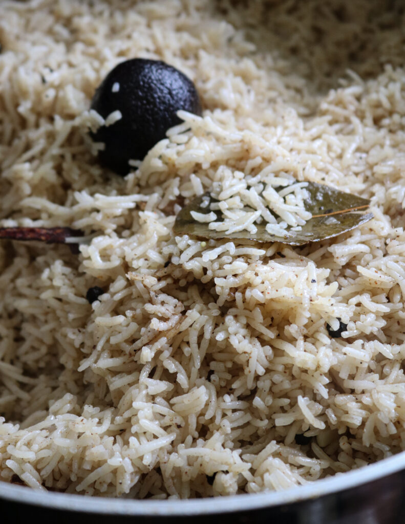 cooked mandi rice with bay leaves and black lime.