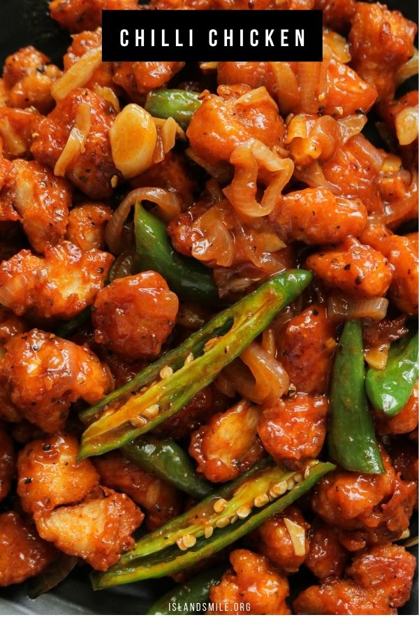 A plate of crispy chilli chicken with green chillies and onions.