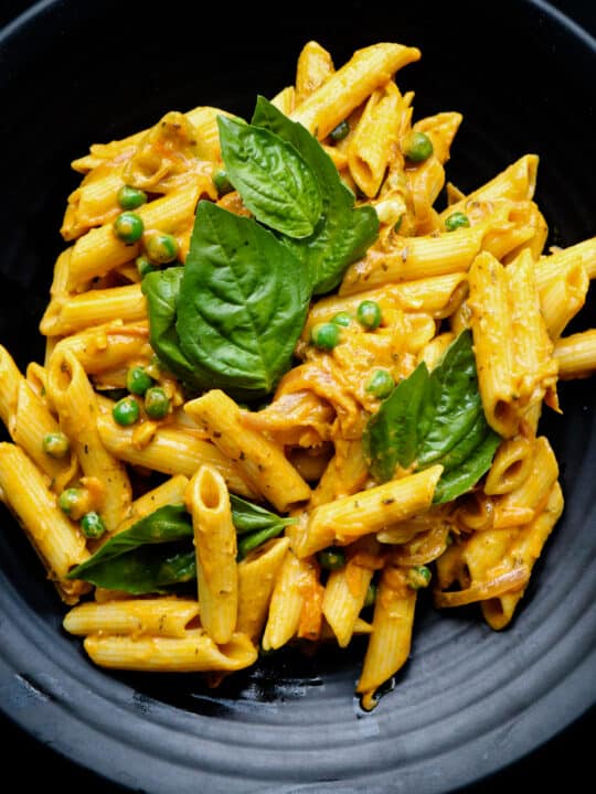 Bowl of creamy coconut curry pasta with penne and green peas