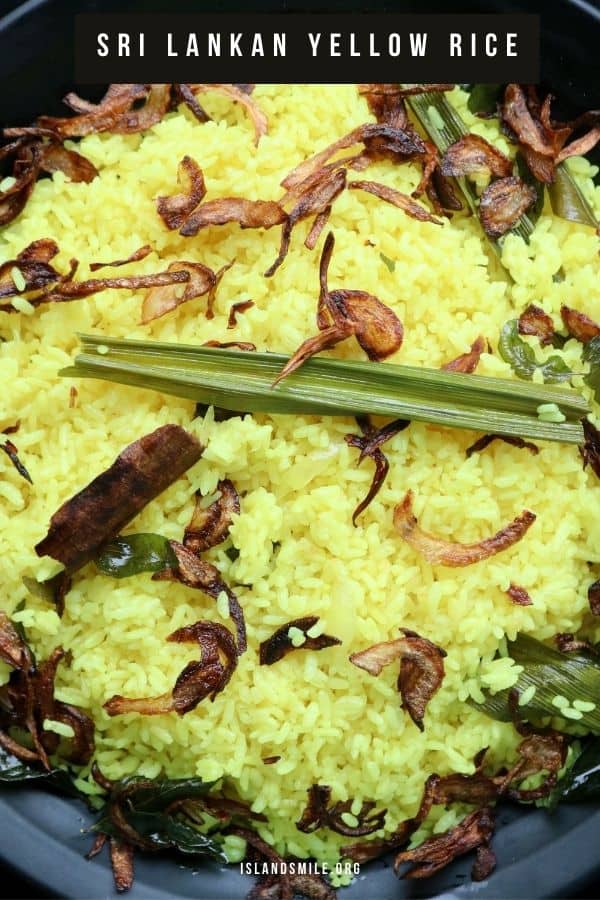 Sri Lankan yellow rice served on a black platter, garnished with fried onions and pandan leaf.