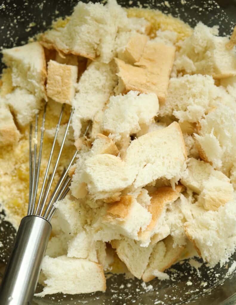 adding the bread pieces to the whisked egg, pineapple pieces to make the pineapple bread pudding.