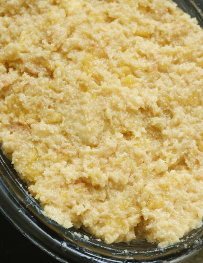 adding the bread and pineapple mixture to a pyrex dish to bake the pineapple bread pudding.