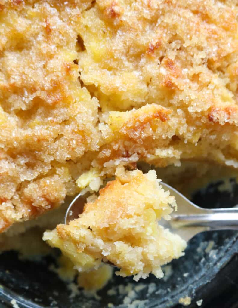 Pineapple bread pudding with a spoon scooping a piece of the bread pudding.