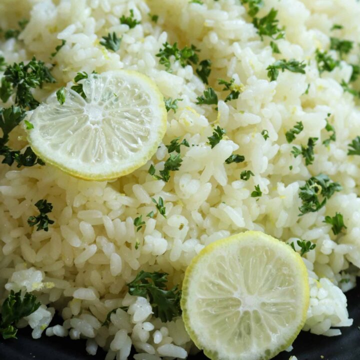 easy lemon rice served over a black platter with lemon slices.