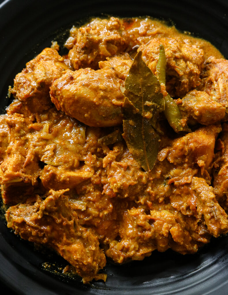 thick chicken curry served into a black plate.
