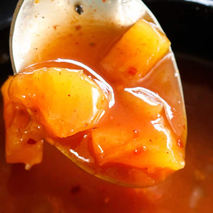 sweet and sour recipe with pineapple chunks scooped in a spoon.