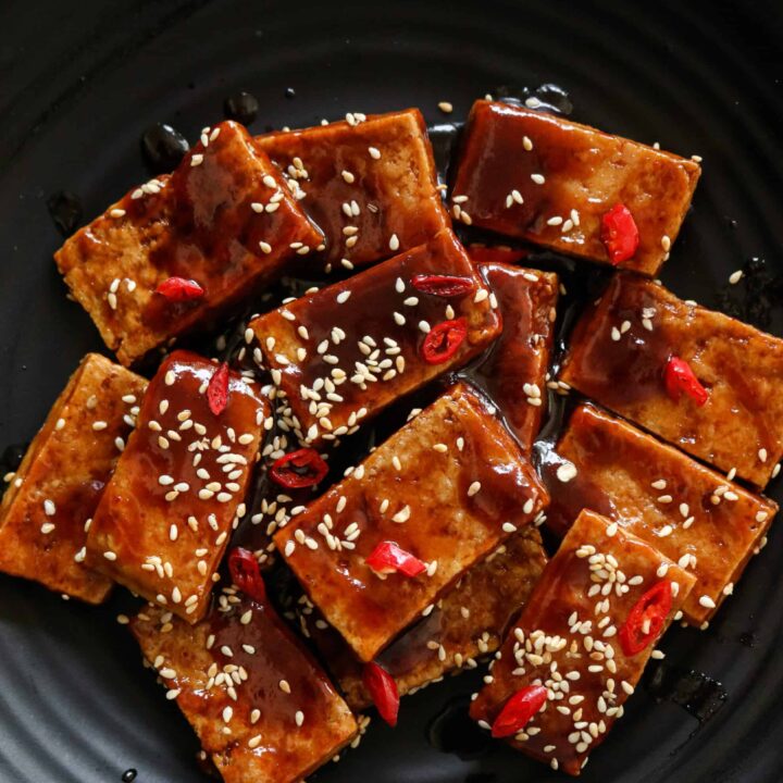 teriyaki tofu served in a platter drizzled with extra teriyaki sauce.