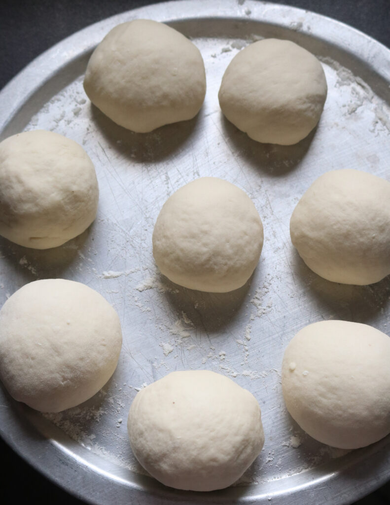 rolling the dough pieces into balls and placed on a silver lid.