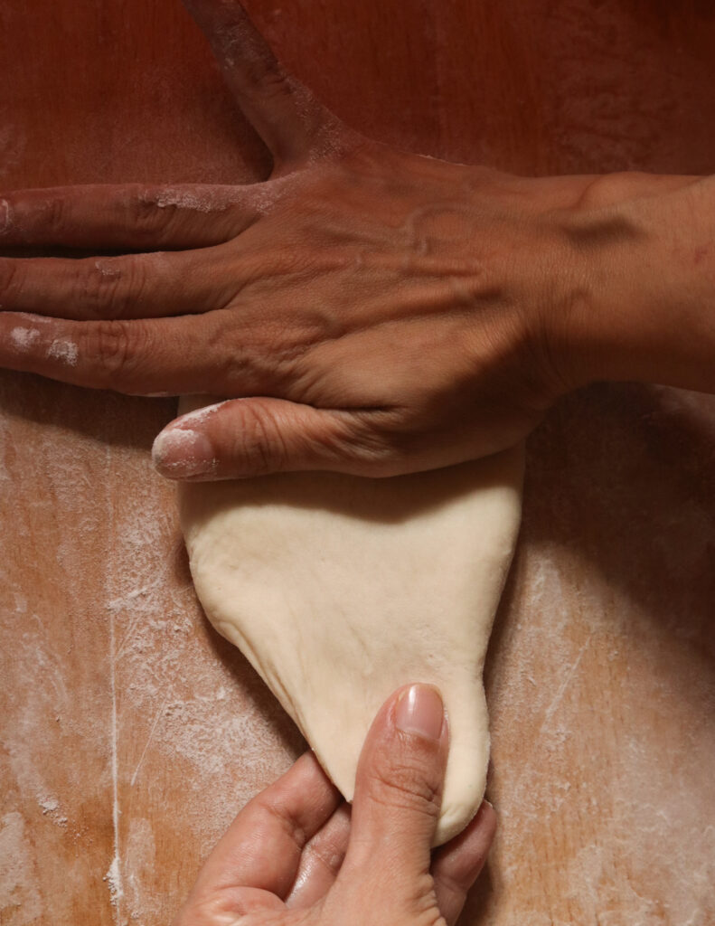 flattening the dough to make the kibula banis.