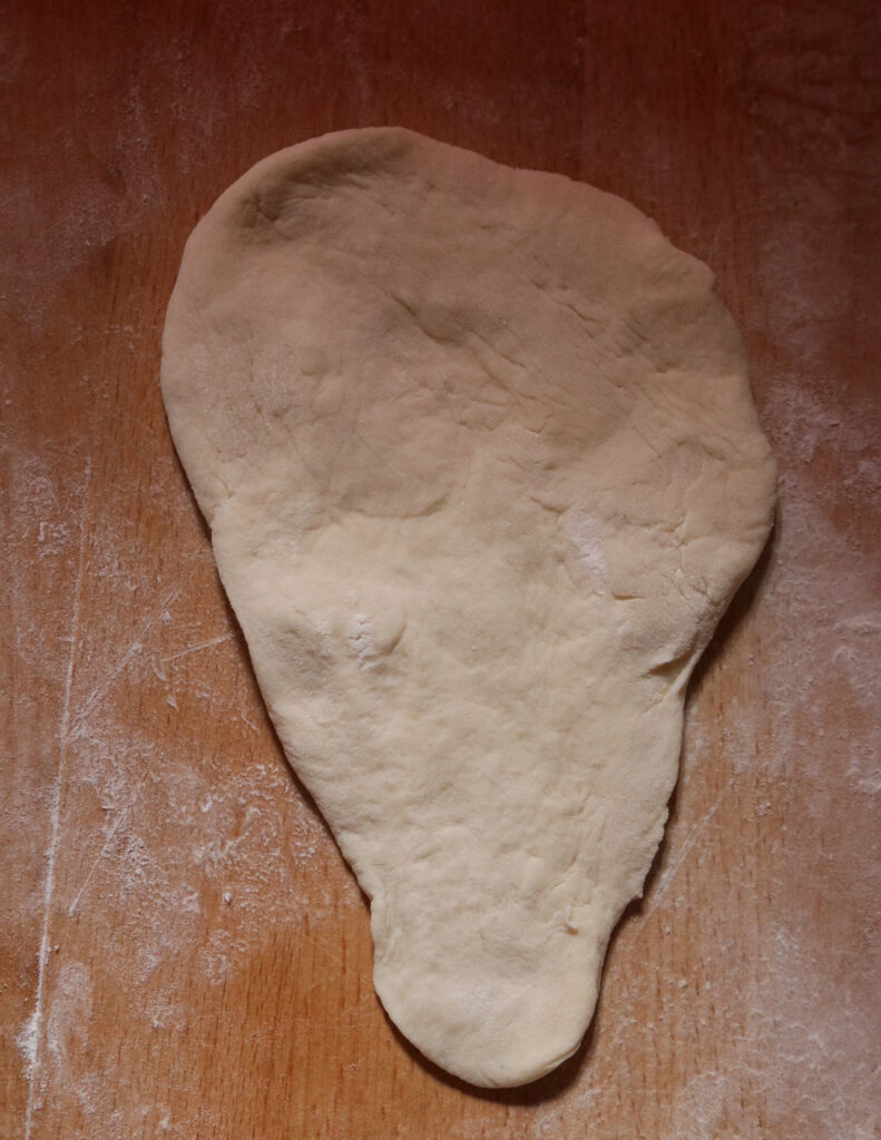 stretched dough on a chopping board.