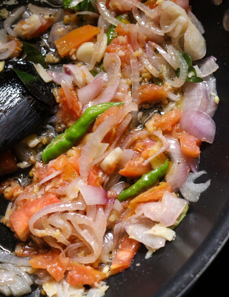 frying onions, garlic, tomato and green chillies in oil to make the soya meat curry