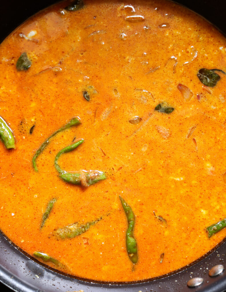 adding coconut milk to the frying spices and onions, tomatoes, green chillies to make soya meat curry