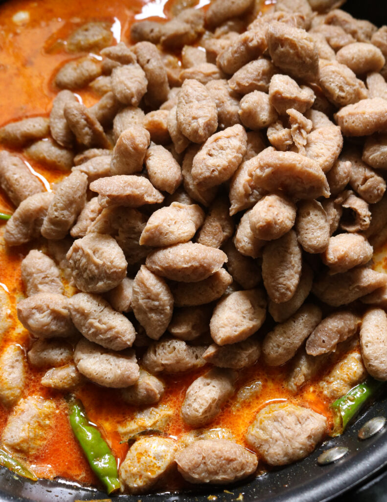 adding boiled soya meat to the coconut milk curry to cook the soya meat .