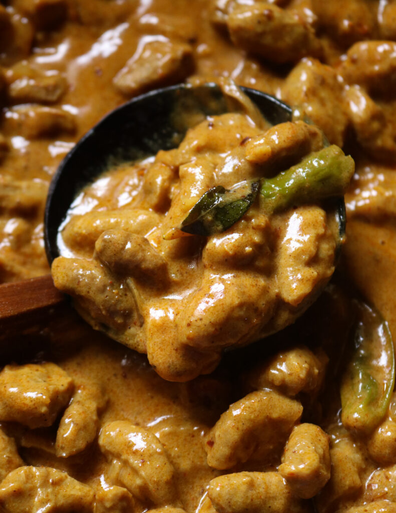 soya meat curry cooked and scooped into a wooden spoon.