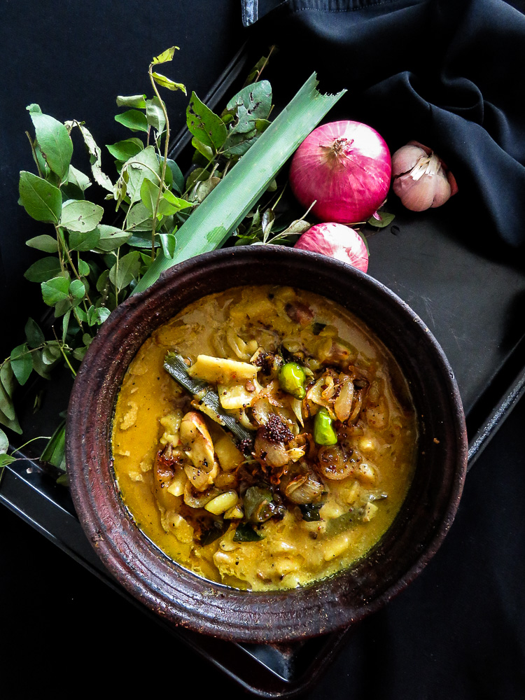 jackfruit curry cooked in a clay pot with tempered mustard, curry leaves, onions on top.