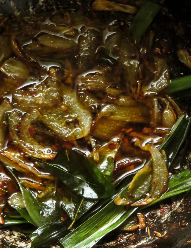 tempered onions, garlic, pandan leaves, curry leaves in oil to garnish the bread fruit curry.