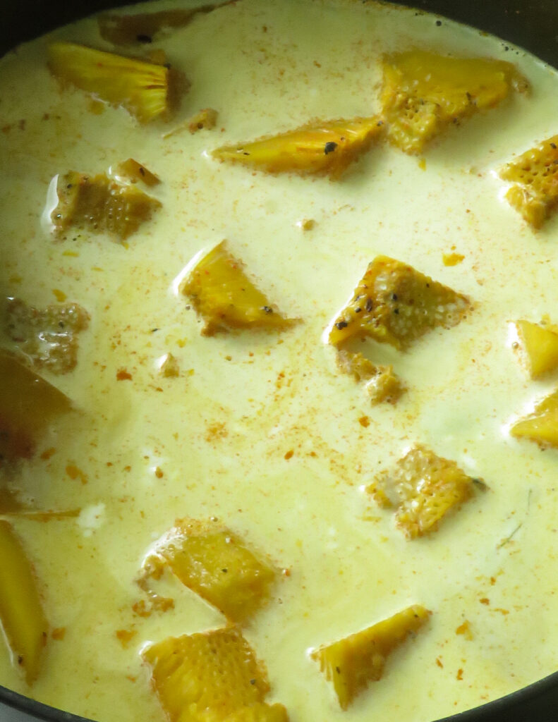 adding coconut milk to cook the boiled bread fruit curry.