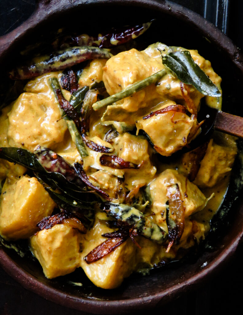 breadfruit curry with tempered onions and curry leaves served on a clay pot.