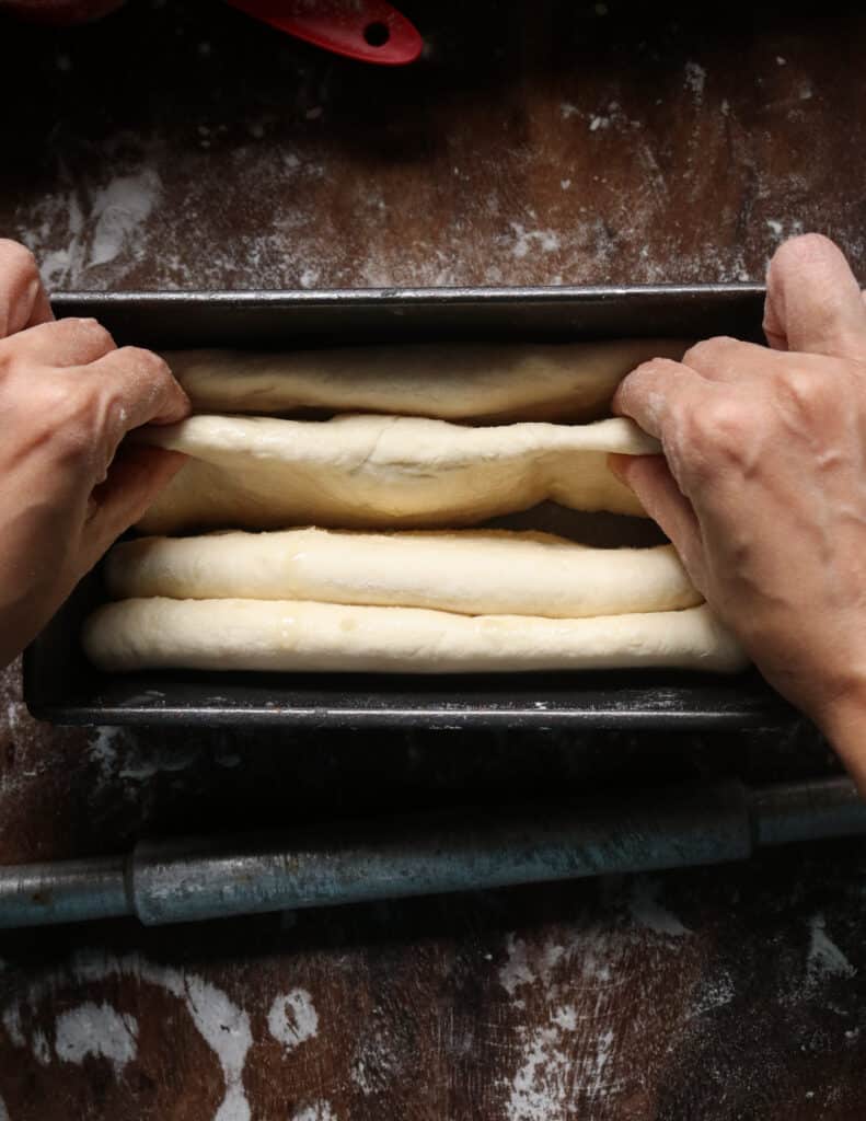 adjusting the shaped dough to bake the roast paan.