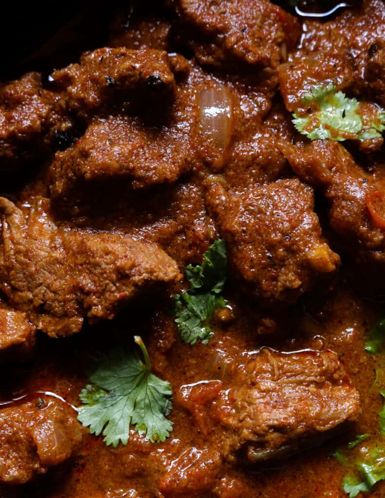 beef vindaloo with a thick gravy and garnished with coriander leaves.