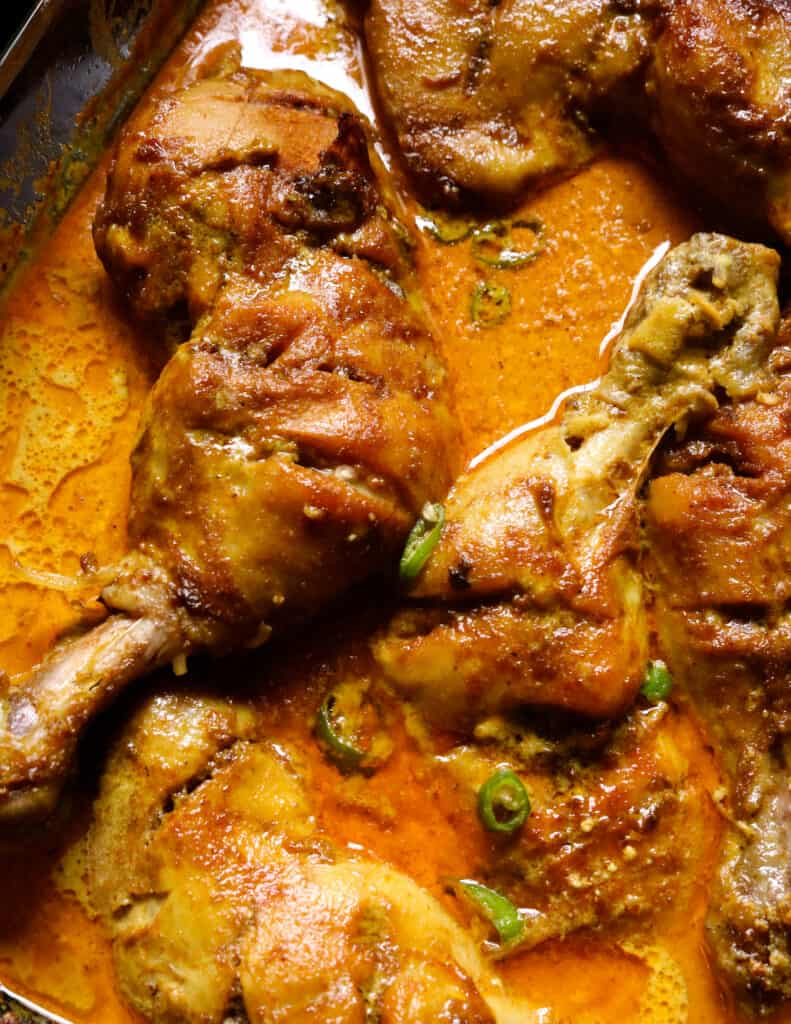 baked curry chicken quarters with gravy in a pyrex dish