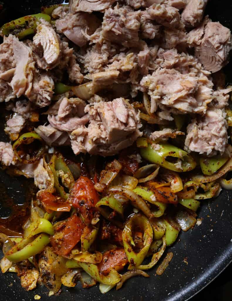 adding chunks of tuna onto the frying ingredients 