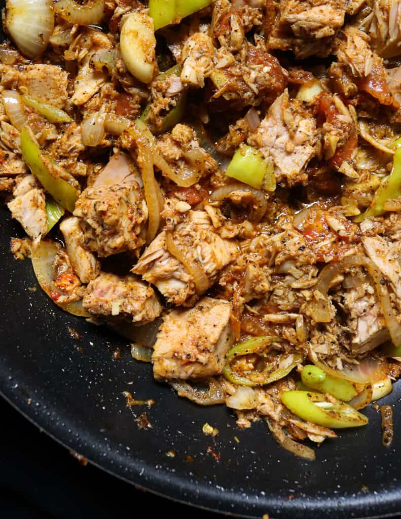 canned tuna stir fry with green peppers, tomatoes cooked in a black frying pan