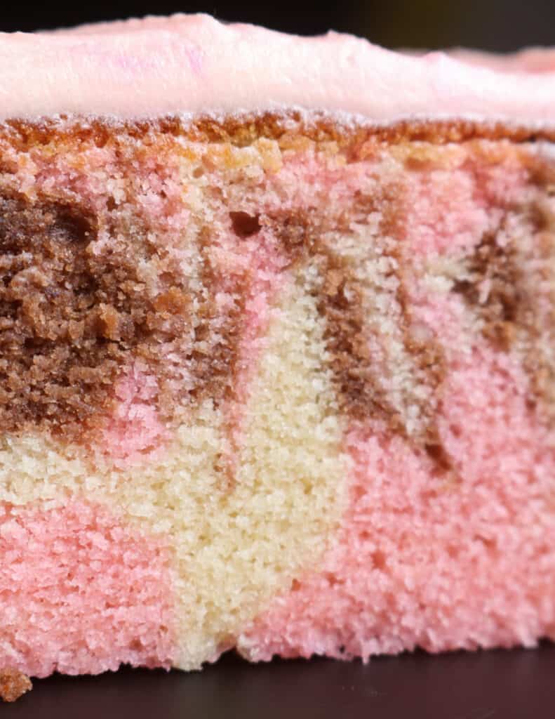 swirls of pink, chocolate and vanilla on the neopolitan cake with pink frosting.