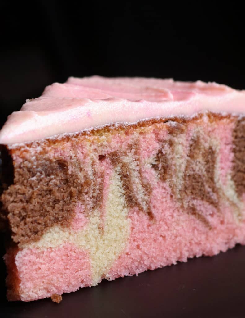 pink marble cake with swirls of vanilla, chocolate and pink cake topped with pink icing.
