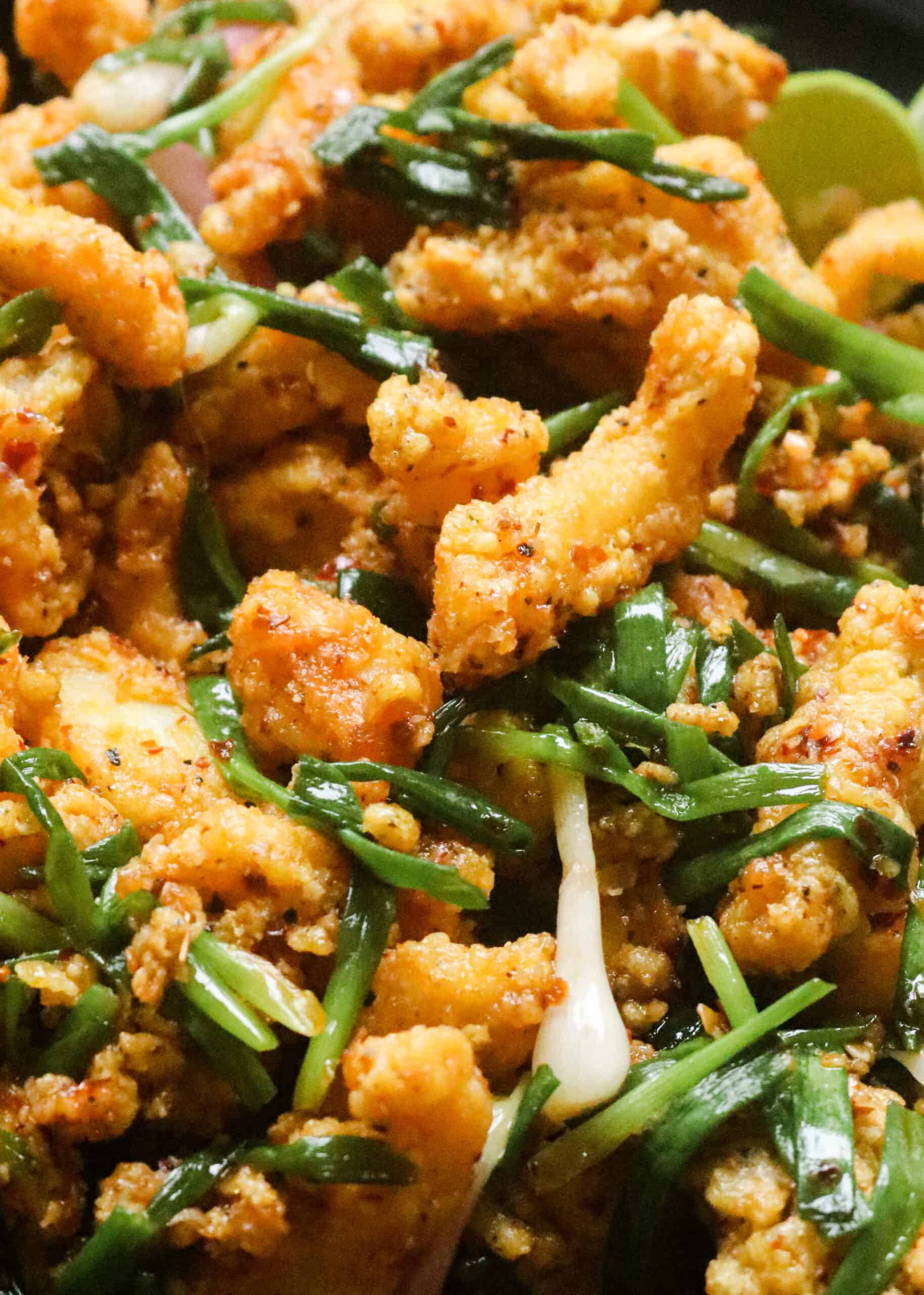 fried cuttlefish with scallions served on a dish.