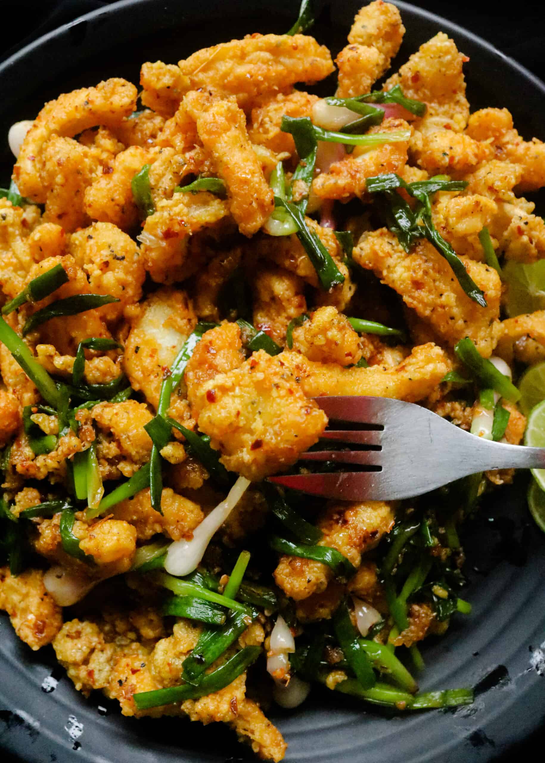 buttery cuttlefish served with scallions served on a plate with a fork