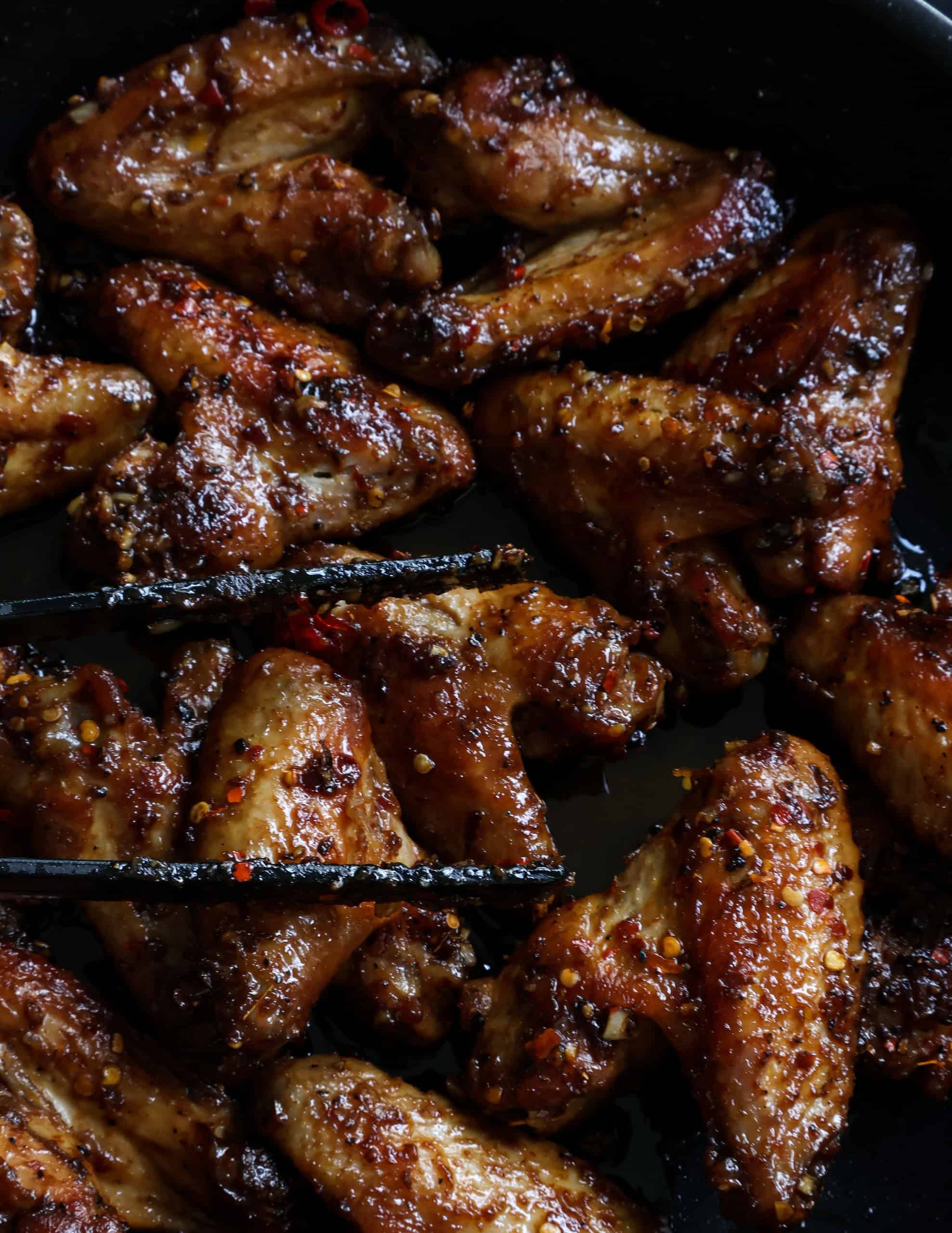 sweet and spicy chicken wings fried in a frying pan.
