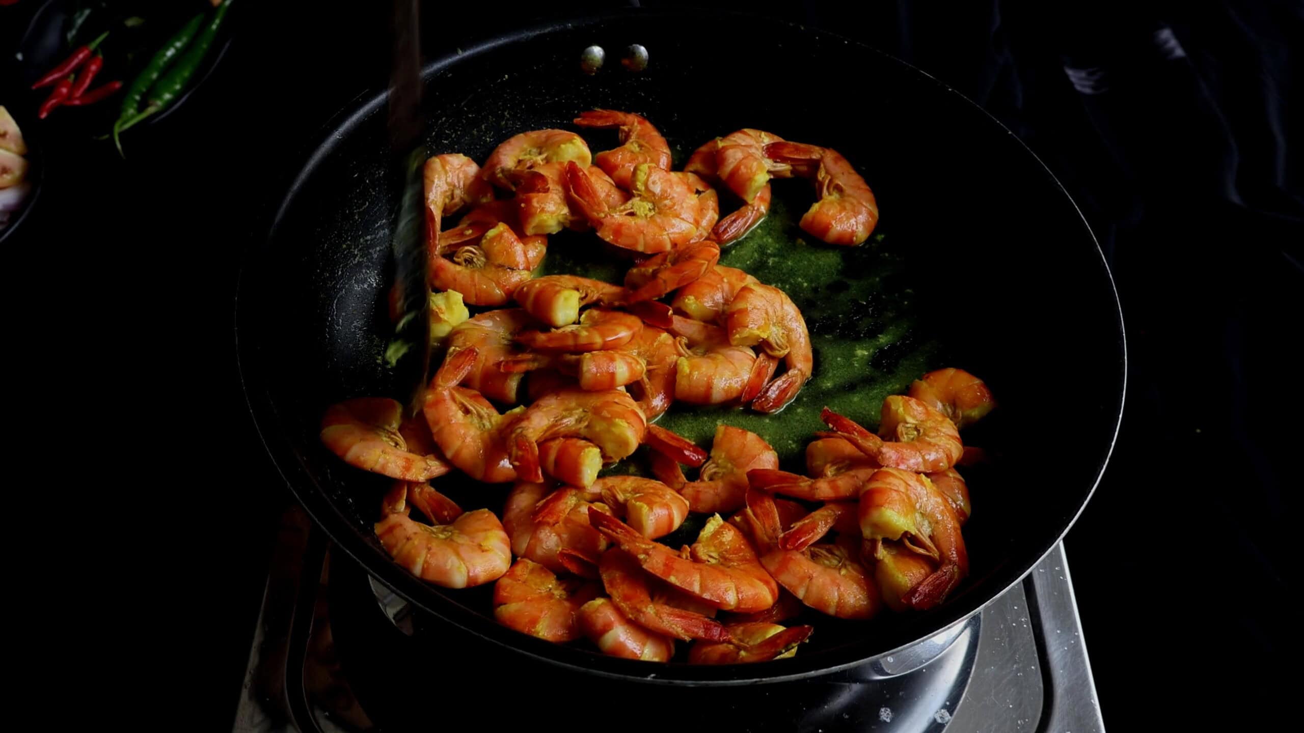 Cooking the prawns until they turn pick to make spicy prawns.